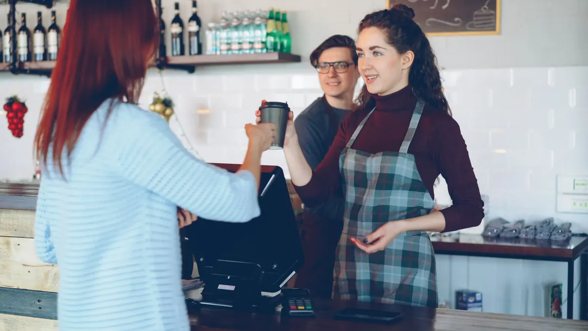 Kundin bestellt in einem Café bei der Mitarbeiterin hinter der Theke