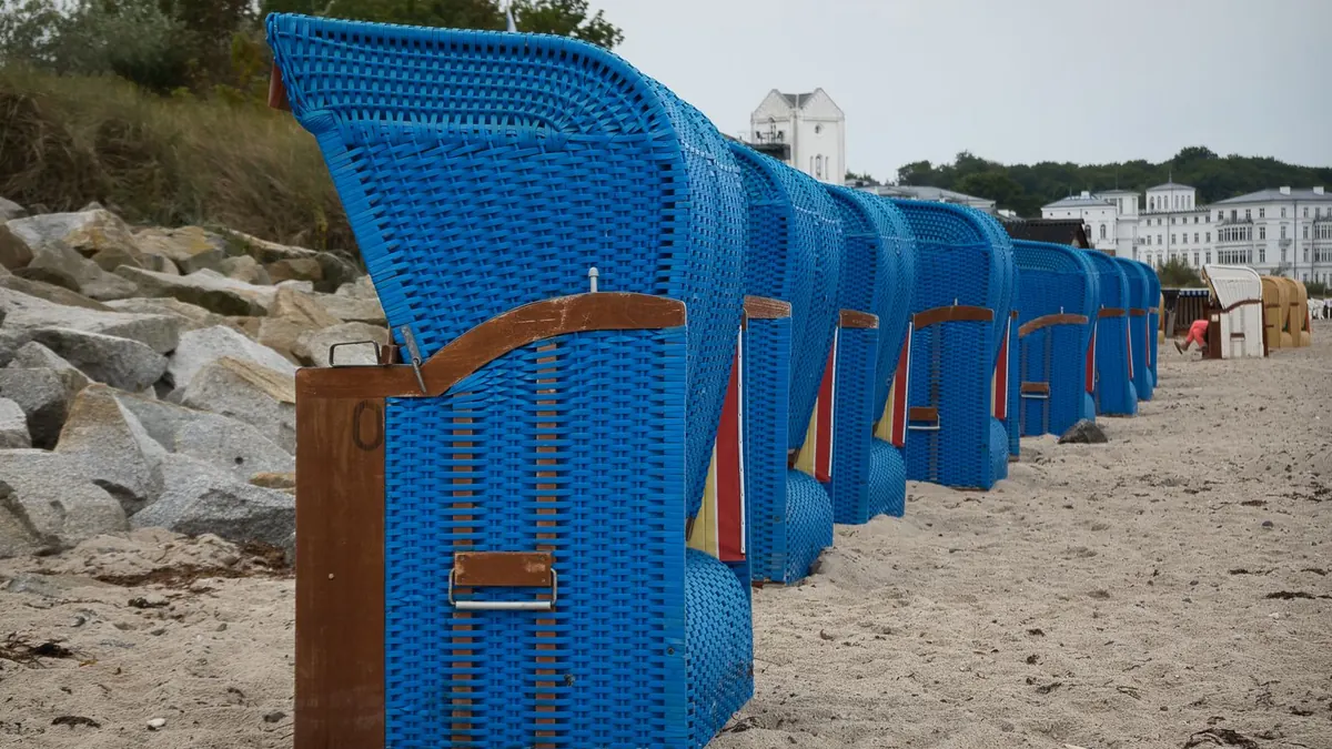 Blaue Strandkörbe stehen in einer Reihe an einem Ostseestrand