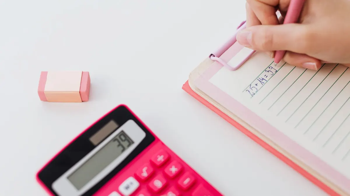 Pinker Taschenrechner und Notizblock mit Stift auf einem hellen Schreibtisch