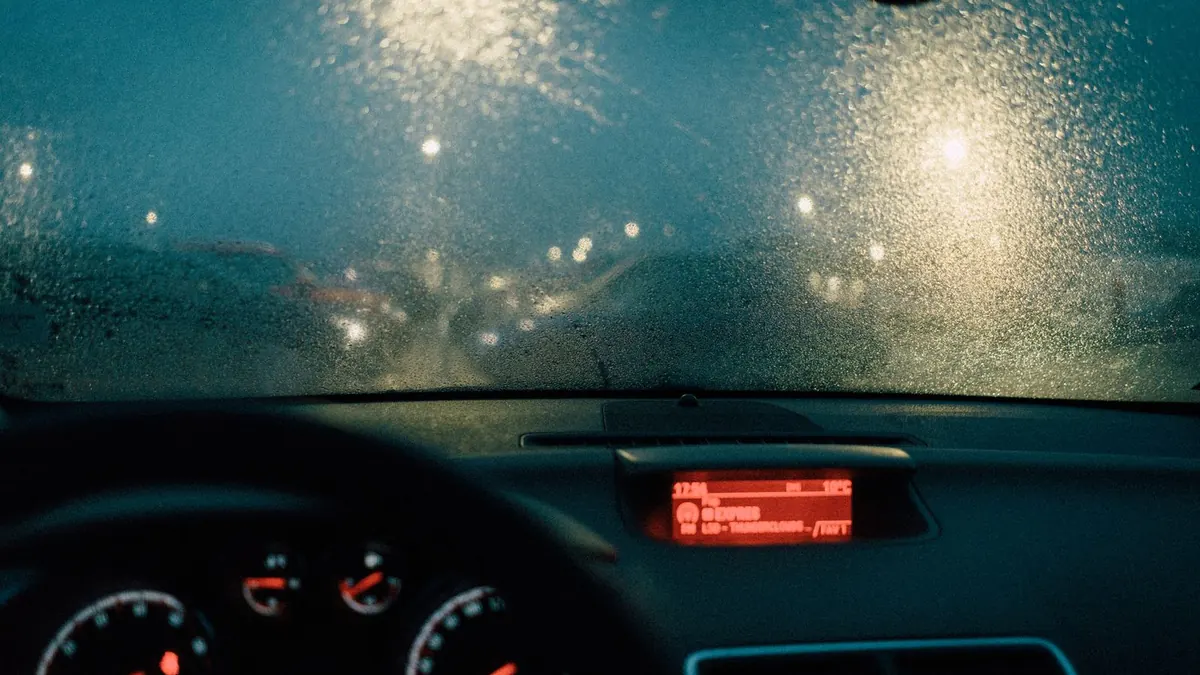 Blick durch die regennasse Windschutzscheibe auf das Armaturenbrett bei Nacht