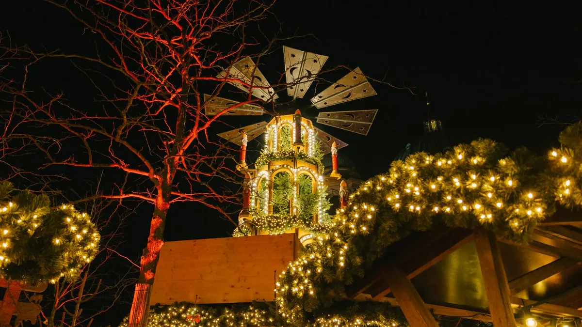Beleuchtete Weihnachtspyramide und Lichterketten auf einem Weihnachtsmarkt am Abend