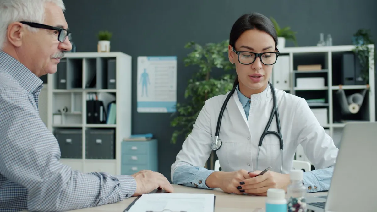 Ärztin spricht in der Praxis mit einem älteren Patienten