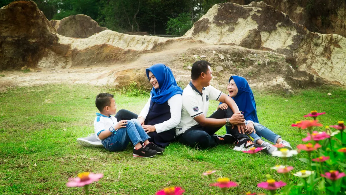 Familie sitzt im Sommer auf einer Blumenwiese vor Felsen