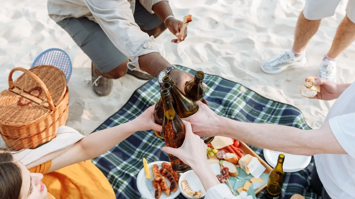 Freunde stoßen bei einem Picknick auf einer Decke am Strand an