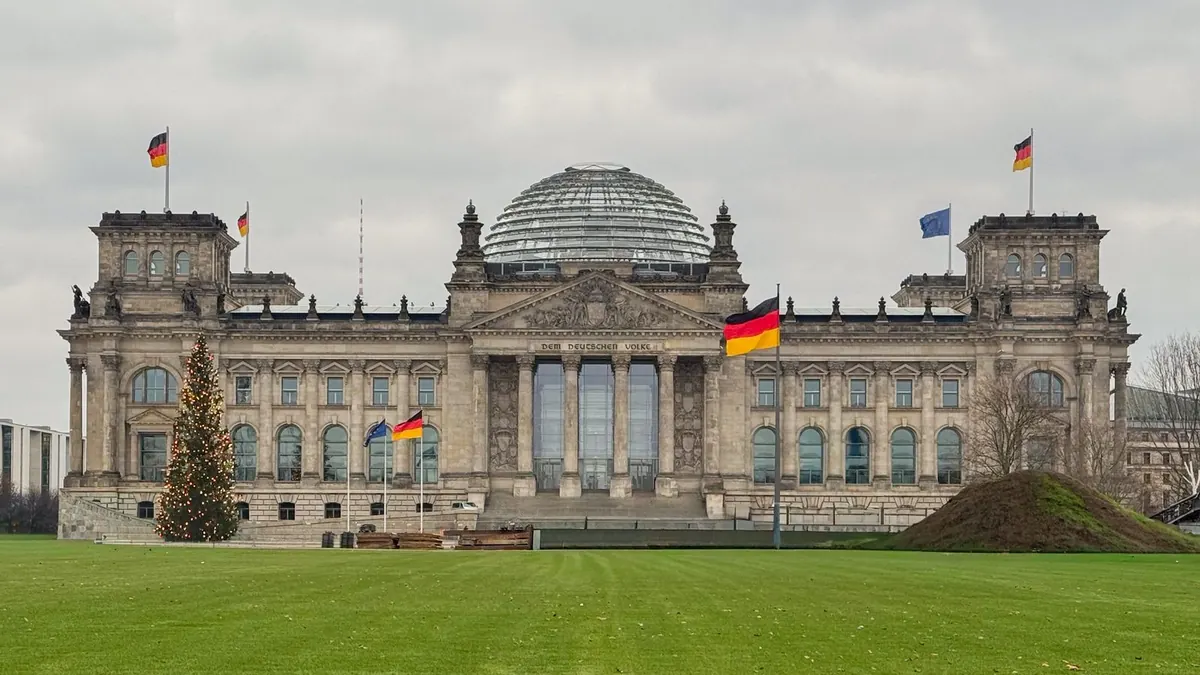 Reichstagsgebäude in Berlin mit Deutschlandfahne und Weihnachtsbaum davor