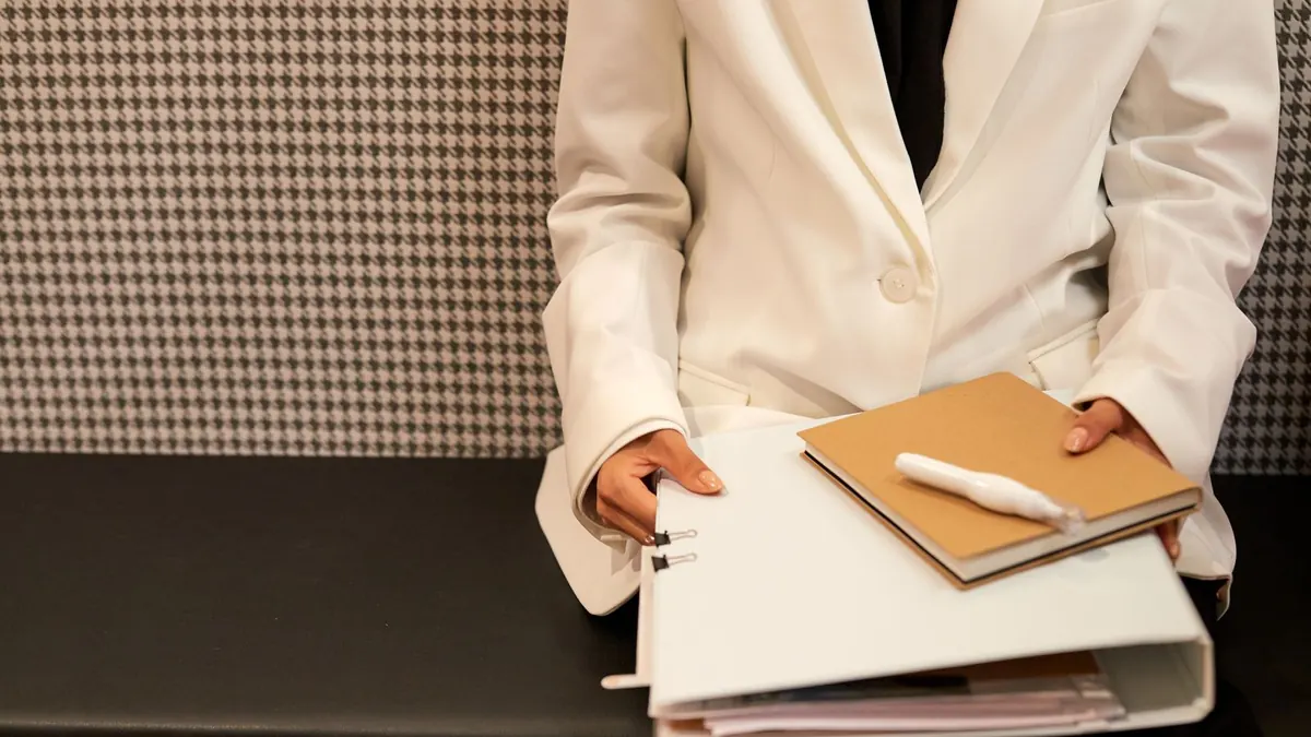 Beraterin im hellen Blazer hält Ordner und Notizbuch in den Händen