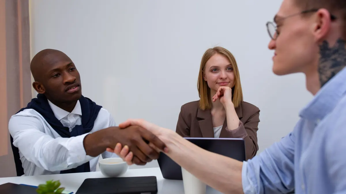 Zwei Personen geben sich nach einem Gespräch im Büro die Hand