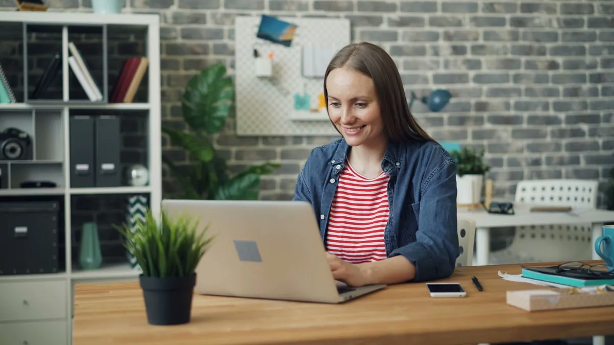 Lächelnde Frau arbeitet in einem hellen Büro an einem Laptop
