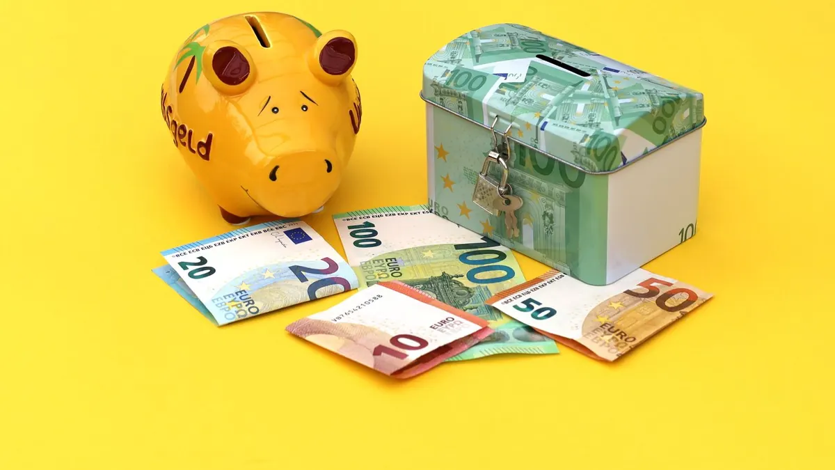 Sparschwein, Spardose und Euroscheine liegen auf gelbem Hintergrund
