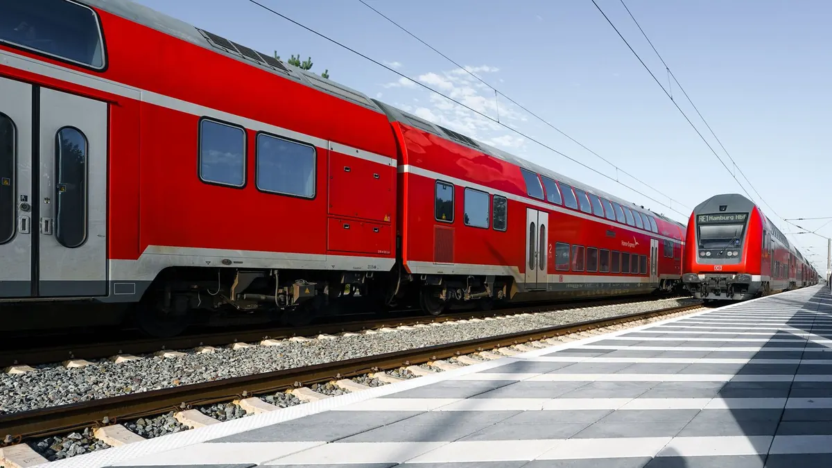 Roter Doppelstock-Regionalzug fährt an einem Bahnsteig entlang der Gleise