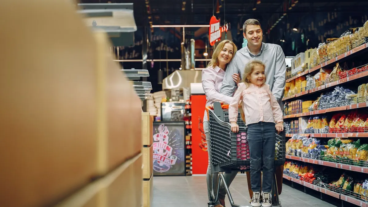 Familie schiebt einen Einkaufswagen durch den Gang eines Supermarkts