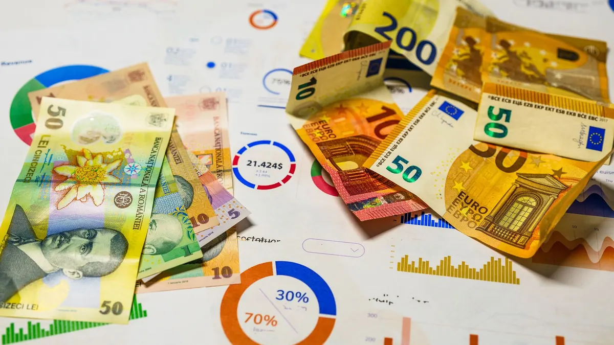 Euroscheine liegen auf Papier mit bunten Diagrammen zu Prozentwerten