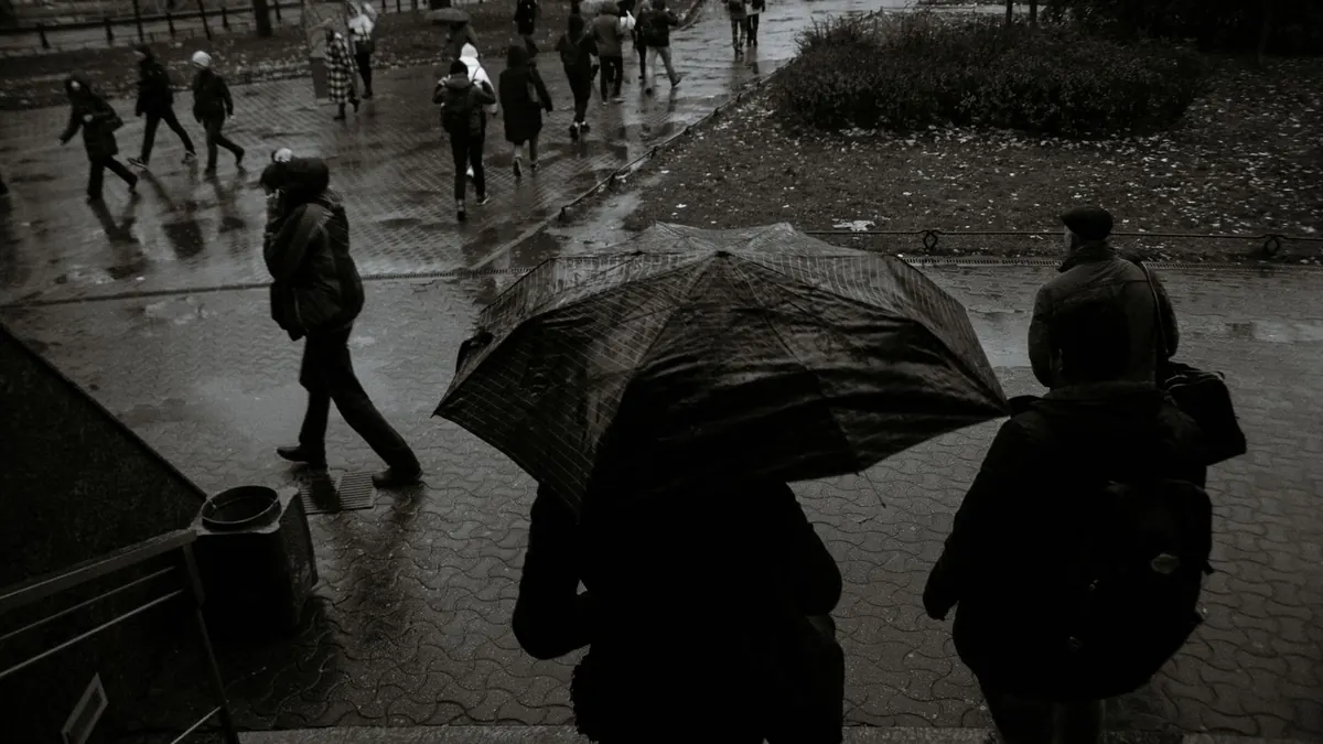 Spaziergänger mit Regenschirmen gehen bei Regen durch eine Stadt