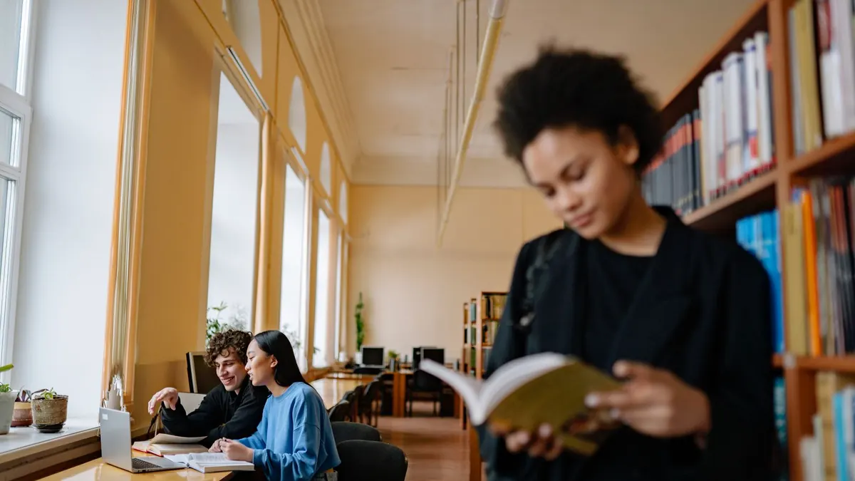 Studentin liest in einem Buch in einer hellen Universitätsbibliothek