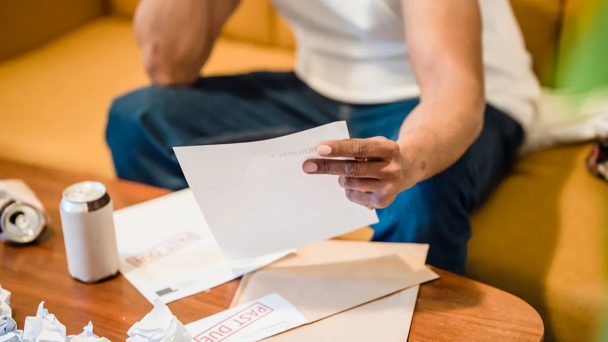 Mann sitzt auf dem Sofa und liest einen Brief neben weiteren Umschlägen