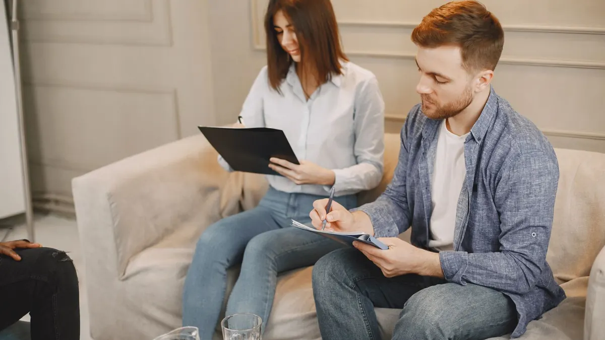 Junges Paar sitzt auf dem Sofa und bespricht gemeinsam Unterlagen
